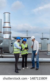 Good looking multiethnic group of workers in a modern building construction site analyzing the plan of construction they wearing the safety helmets.