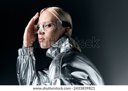 good looking peculiar woman in futuristic glasses looking at camera on dark gray background