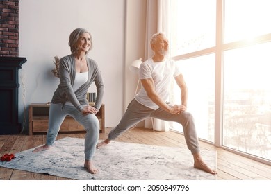 Good looking senior couple in sports clothing exercising and smiling while spending time at home - Powered by Shutterstock