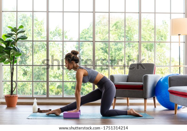 Good looking woman\
practicing yoga at home use block for more comfortable and easier\
for practise
