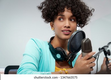 Good Looking Young Black Female Making An Online Podcast Recording For Her Online Show. Attractive Millennial African American Business Woman Using Headphones In Front Of Microphone For Radio Program.