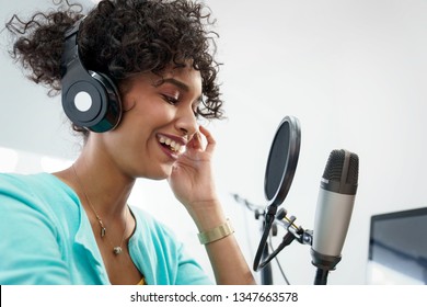 Good Looking Young Black Female Making An Online Podcast Recording For Her Online Show. Attractive Millennial African American Business Woman Using Headphones In Front Of Microphone For Radio Program.