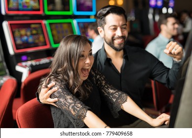 Good looking young couple celebrating and looking excited about hitting the jackpot in a slot machine at a casino