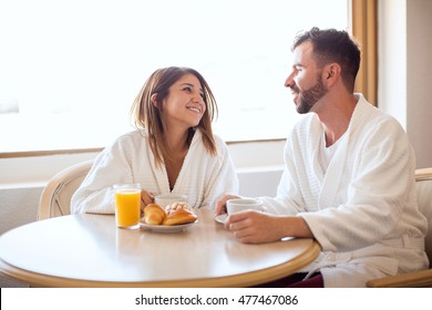 Good looking young couple wearing robes and eating breakfast in their hotel room - Shutterstock ID 477467086