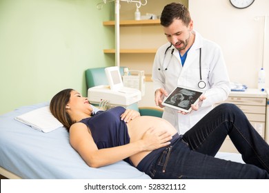 Good looking young doctor using a tablet computer to display an ultrasound image to a pregnant patient