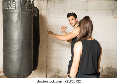 Good looking young man giving some technique advice to a woman in a boxing gym - Powered by Shutterstock