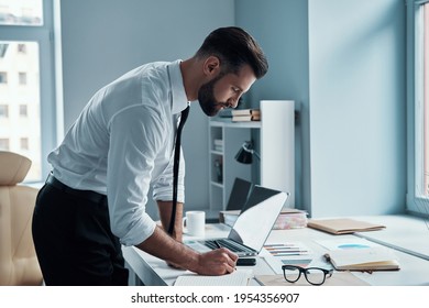 Good Looking Young Man In Shirt And Tie Working With Documents In Office