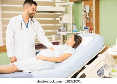 Good looking young obgyn doctor checking up on a pregnant woman while doing rounds in a hospital
