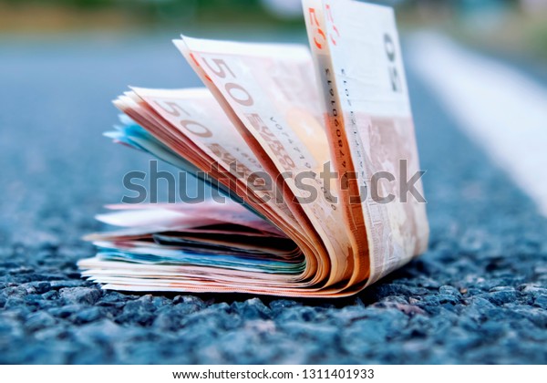 Good luck to find money as a symbol of profit.\
Close up Euro banknotes on the road. Money, wealth, business,\
success concept.