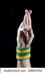 Good Luck Fingers Crossed On Hand Of An Athlete With Brazil Colors Wristband On Black Background