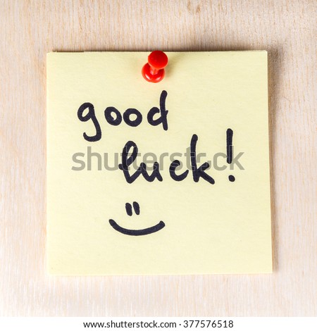 Good luck note on paper post it pinned to a wooden board