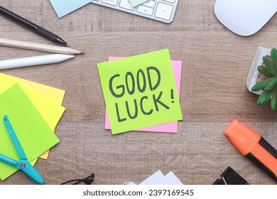 Good Luck text on sticky notes with office stationery over wooden background