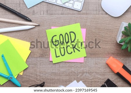 Good Luck text on sticky notes with office stationery over wooden background