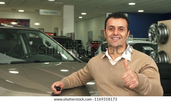 A\
good man examines the car salon and shows a thumbs\
up