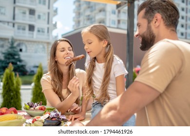 Good Mood. Young Family Having Dinner Outside And Looking Cheerful