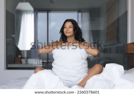 Good morning for adorable young happy woman hugging pillow on comfortable bed with silky linens. High quality photo for advertisement 