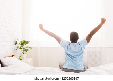 Good Morning! African-american Man Waking Up In Bed And Stretching His Arms, Back View, Copy Space