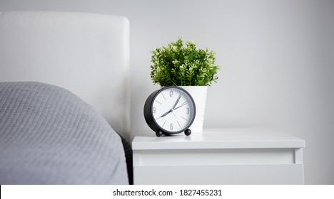 Good Morning Concept - Modern Alarm Clock And Houseplant On Bedside Table