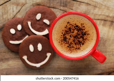 Good morning or Have a nice day message concept - bright red cup of frothy coffee with smiling chocolate cookies