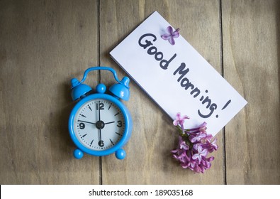 Good Morning Note, Lilac Flowers And Old-styled Clock On The Wooden Table