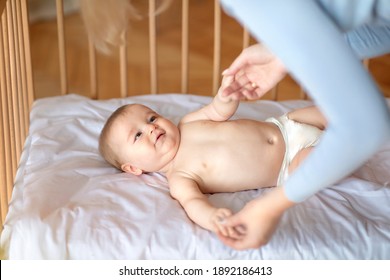 Good Morning Sunshine. Smiling Little Baby Laying In Cot, Holding Mom's Hands, Ready To Wake Up. Top View Of Cute Blonde Toddler Waking Up, Lying In Wooden Baby Bed, Grabbing Mother Fingers