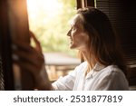 Good morning, young happy smiling woman opening bedroom window looking at the sunlight enjoying the warm sunshine, happy morning  carefree lifestyle 