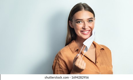 Good News. Beautiful Girl Taking Her Surgeon Mask Off Isolated Over White Studio Backgound, Copy Space, Banner