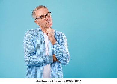 Good Offer. Portrait of pensive mature man in glasses looking up aside at free copy space, touching his chin, isolated over blue studio background. Thoughtful adult guy thinking and making decision - Powered by Shutterstock