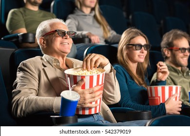Good Old Movies. Cheerful Senior Man Wearing 3D Glasses Grabbing Popcorn While Enjoying A Movie With His Family At The Cinema Copyspace Seniority Happiness Industry Fun Leisure Concept