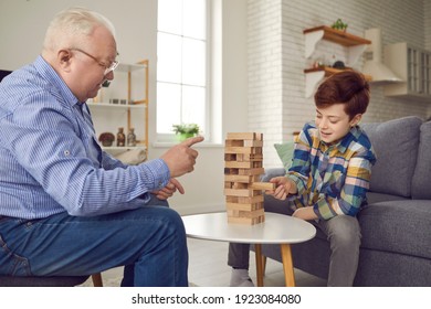 Good Older Friend. Happy Grandfather And Grandson Playing And Enjoying Fun Time Together. Experienced Senior Man Gives Little Kid Useful Winning Strategy Advice While Playing Board Game At Home