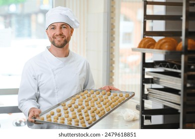 Good quality.Picture of mature cheerful male employee in sterile clothes standing in bright food factory . Holding tray full with fresh cookies and gesturing with his hand that quality is good. - Powered by Shutterstock