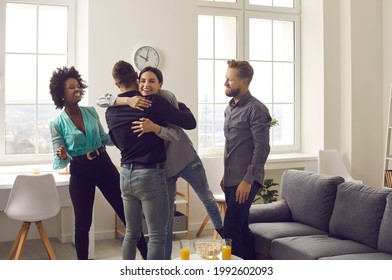 It's Good To See You After Such A Long Time. Group Of Diverse Young People Happy To Meet Their Friend At A Reunion Party At Home. Bunch Of Excited Men And Women Hugging Friend Who They Missed So Much