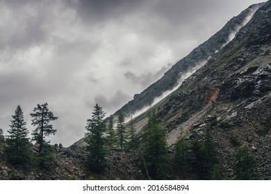 Good Shot Of Rockfall On Rocky Mountain Steep Slope And Long Trail Of Dust. Good Moment Of Dangerous Scene With Falling Stones And Boulder From Rocks. Rockfall In Mountains. Dusty Plume Of Rockfall.