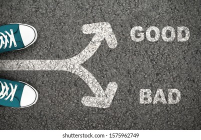 Good Versus Bad Written On The Road. Man Standing On Crossroad With Arrows Showing Different Directions.