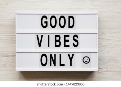 'Good vibes only' words on a modern board on a white wooden background, top view. From above, overhead, flat lay. Close-up.