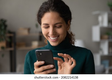 Good virtual conversation. Smiling millennial latina lady touch smartphone screen text answer on friend message scroll social media networking. Happy young female online shopper buy goods in one click - Shutterstock ID 2082214138