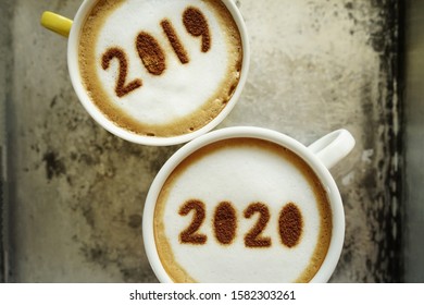 Goodbye 2019 Hello 2020 Theme Coffee Cups With Number 2020 And 2019 Over Frothy Surface Serving In Rustic Aluminum Tray With Coffee Beans. New Year New You, Holidays Food Art Concept. (top View)