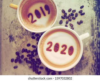 Goodbye 2019 Hello 2020 Theme Coffee Cups With Number 2020 And 2019 Over Frothy Surface Serving In Rustic Aluminum Tray With Coffee Beans. New Year New You, Holidays Food Art Concept. (top View)