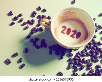 Goodbye 2020, A Year That Many Want Time To Flies By. Holidays Food Art Theme Coffee Cup With Coffee Stain And Number 2020 At The Bottom Of Cup On Green Background With Coffee Beans. New Year New Life