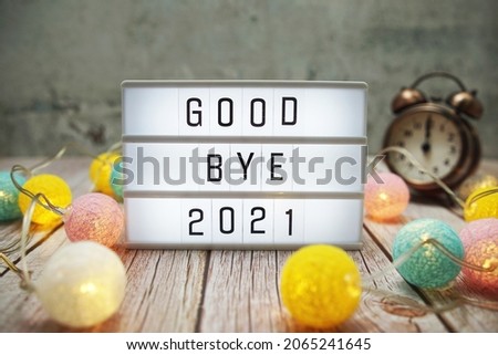 Goodbye 2021 text on lightbox on wooden background