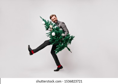 Good-humoured office worker dancing after party. Indoor shot of caucasian man holding christmas tree. - Powered by Shutterstock