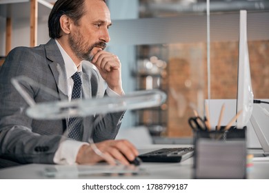 Good-looking bearded man working on modern computer while sitting at the table in office - Shutterstock ID 1788799187