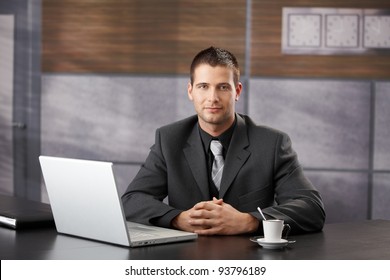 Goodlooking Confident Manager Sitting In Fancy Office, Smiling.?