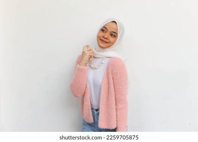 Good-looking hijab young woman spraying perfume on her neck and smiling with delightment on grey background. - Powered by Shutterstock