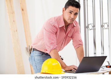 Good-looking Hispanic Contractor Doing Some Work On A Laptop On Site