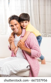 Goodlooking Indian/Asian Playful Father Son Having Good Time At Home While Sitting Over Sofa