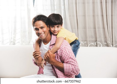 Goodlooking Indian/Asian Playful Father Son Having Good Time At Home While Sitting Over Sofa