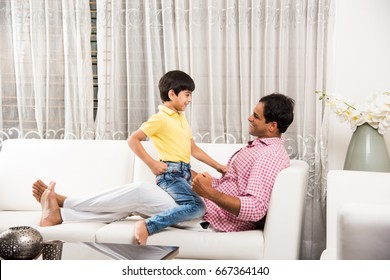 Goodlooking Indian/Asian Playful Father Son Having Good Time At Home While Sitting Over Sofa