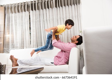 Goodlooking Indian/Asian Playful Father Son Having Good Time At Home While Sitting Over Sofa