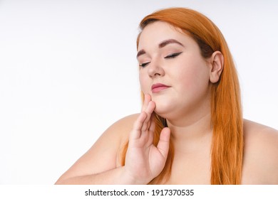Good-looking young fat woman in spa towel touching her face isolated over white background